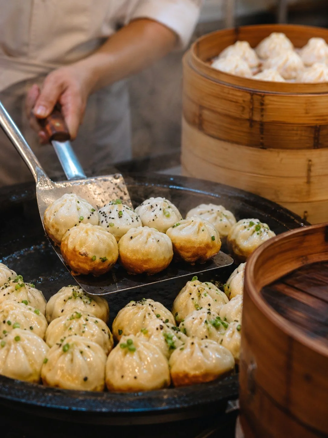 Shengjian dumplings sizzling in a pan, a Shanghai breakfast ritual